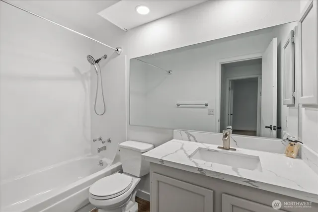 a bathroom with a granite countertop sink toilet vanity mirror and bathtub