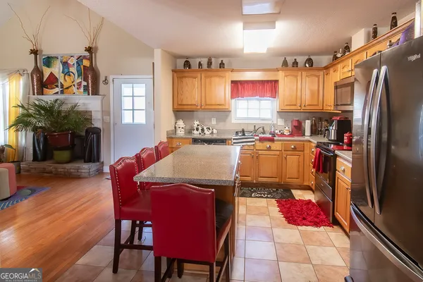 a kitchen with stainless steel appliances granite countertop a dining table chairs refrigerator and sink