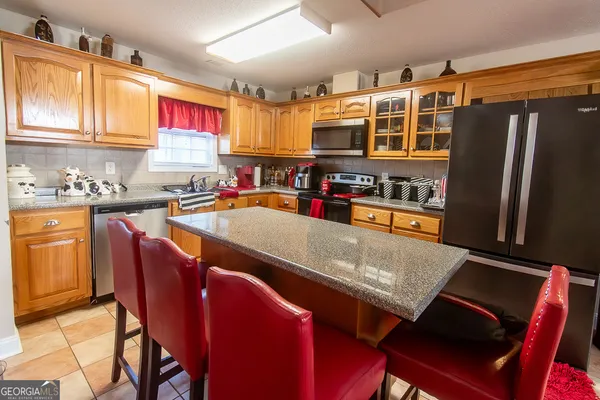 a kitchen with stainless steel appliances granite countertop a table chairs and a refrigerator