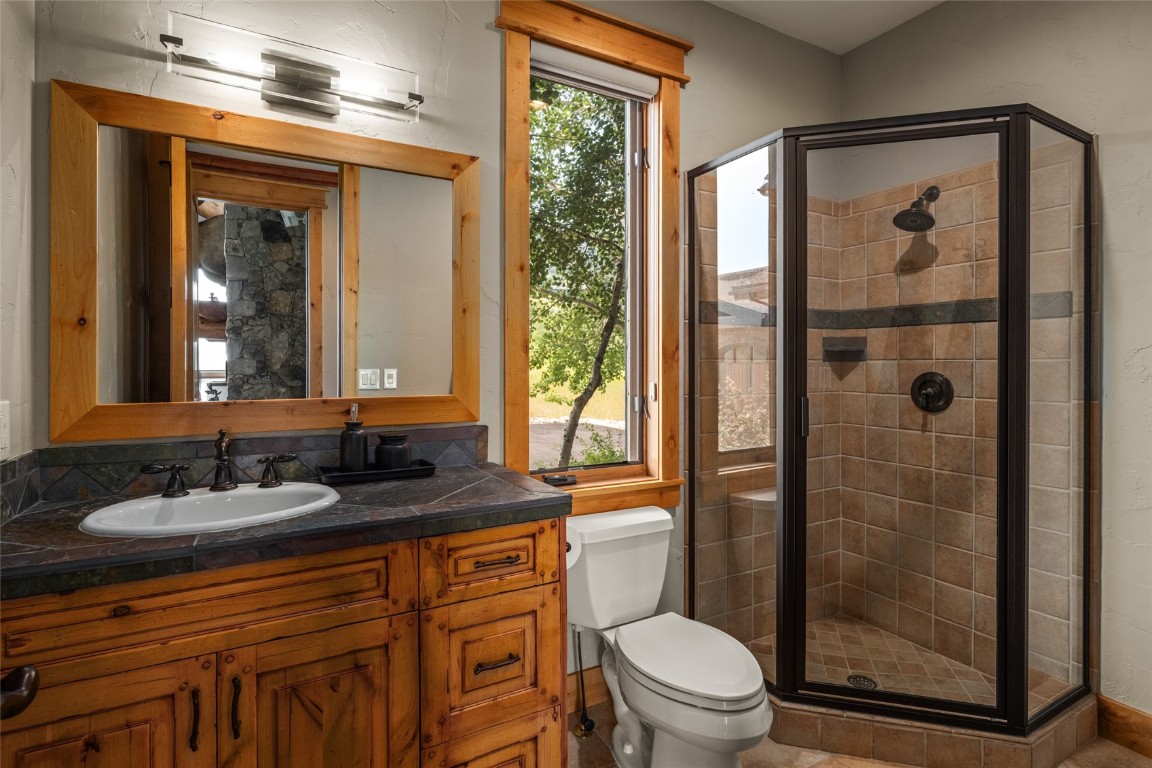 31105 Country Side Road Steamboat Springs, CO 80487 - Photo 21 of 50 a bathroom with a granite countertop sink toilet a mirror and shower