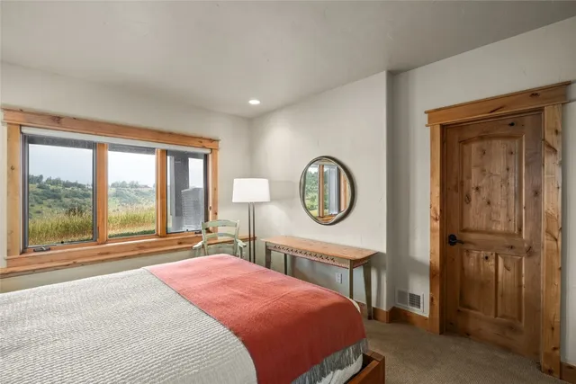 a bedroom with a bed a mirror and a large window