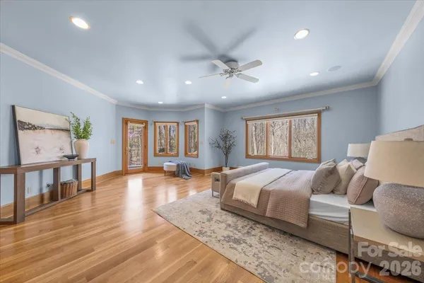 a spacious bedroom with a large bed a chandelier and windows