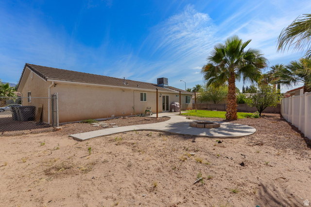 664 East Springhill Drive Washington, UT 84780 - Photo 20 of 21 Spacious backyard featuring a circular concrete patio with a built-in fire pit, a mature palm tree, and a section of green lawn