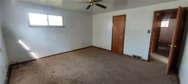 an empty room with a window and a ceiling fan
