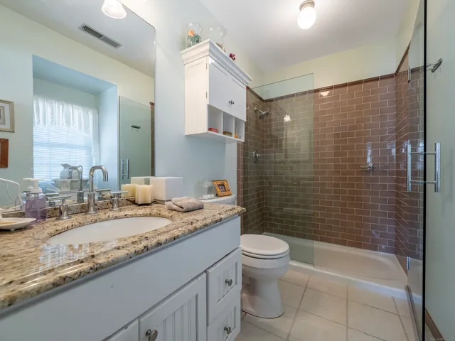 a bathroom with a granite countertop sink a toilet and shower