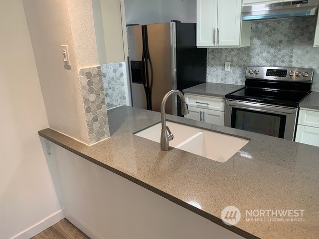 3915 Mason Loop Road Tacoma, WA 98409 - Photo 5 of 38 a kitchen with stainless steel appliances granite countertop a sink a stove and a refrigerator