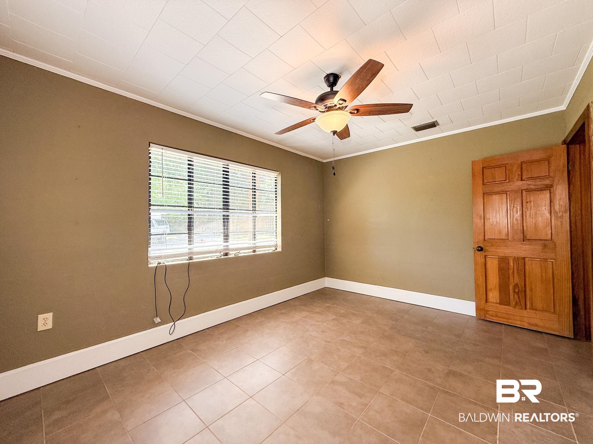 18711 Keller Road Foley, AL 36535 - Photo 17 of 38 Spacious room featuring tile flooring, a window with blinds, a ceiling fan with light fixture, and a paneled wooden door
