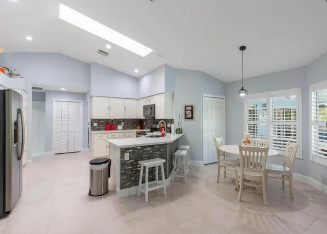 a kitchen with a dining table chairs and large window