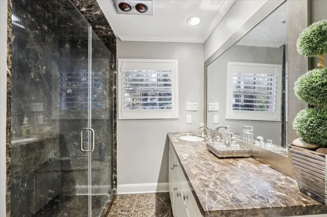 a bath room with a granite countertop sink a mirror and a shower