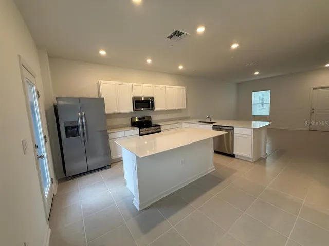 a large kitchen with stainless steel appliances a sink a refrigerator and a stove