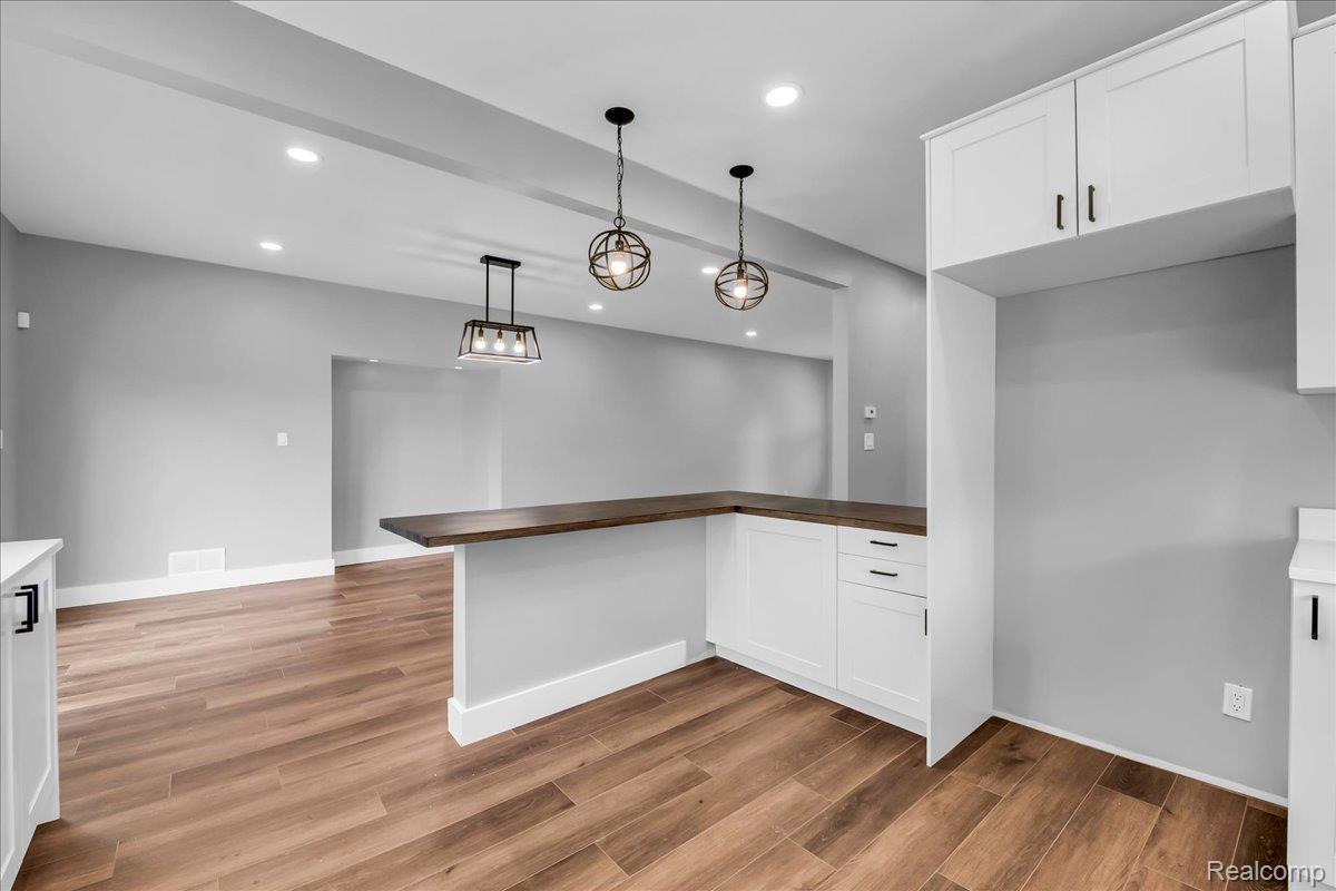 2181 Harding Street Detroit, MI 48214 - Photo 13 of 32 Kitchen featuring a peninsula, white cabinetry, hanging light fixtures, and light wood-style flooring