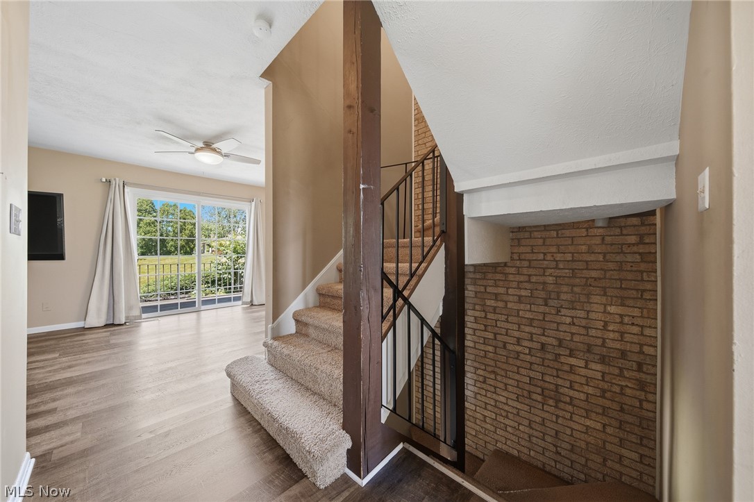 824 South Chillicothe Road, Unit 2 Aurora, OH 44202 - Photo 15 of 42 Carpeted staircase with black metal railings, flanked by a full-height brick accent wall
