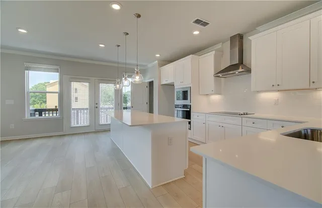 a large kitchen with stainless steel appliances kitchen island wooden floors and white cabinets