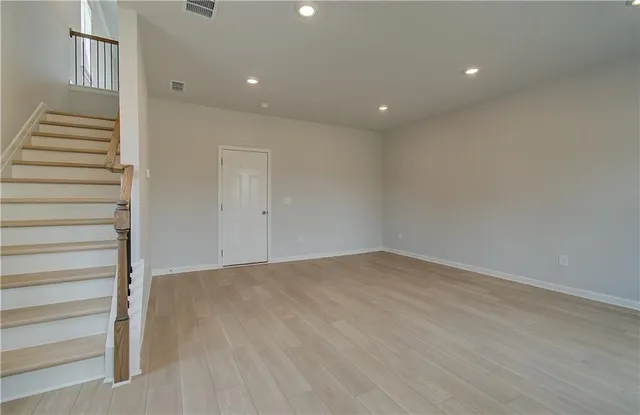 a view of an empty room with wooden floor and entryway