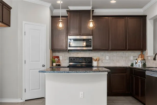 a kitchen with stainless steel appliances granite countertop a sink a stove a microwave and cabinets
