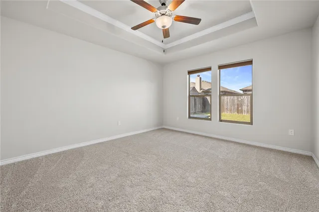 an empty room with windows and ceiling fan