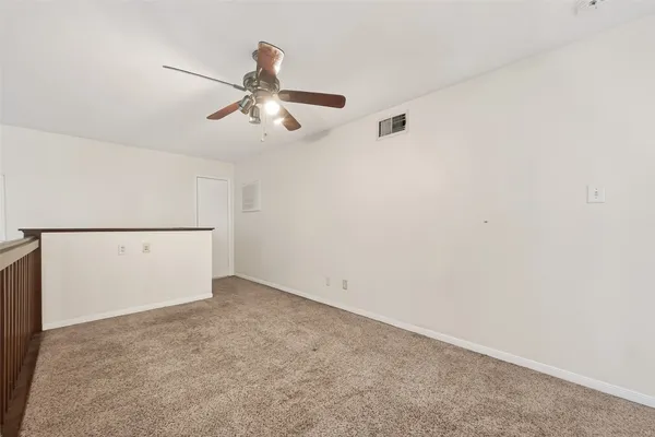 an empty room with a ceiling fan and carpet