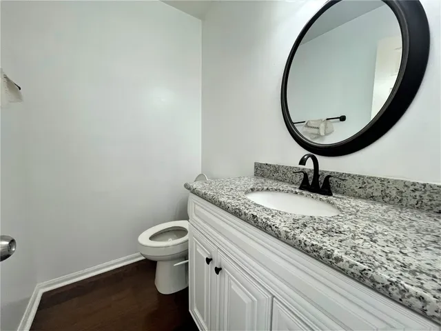 a bathroom with a granite countertop toilet and a sink