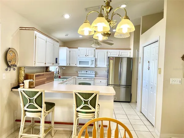 a kitchen with stainless steel appliances granite countertop a sink a stove a refrigerator cabinets and chairs