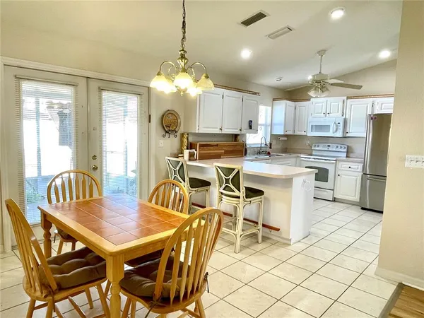 a dining room filled chandelier and kitchen view