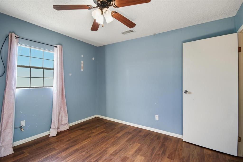 413 Charnel Street Clyde, TX 79510 - Photo 21 of 31 an empty room with wooden floor chandelier fan and windows