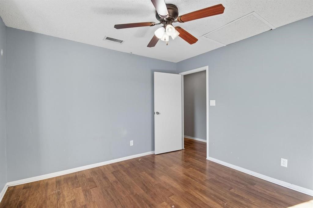 413 Charnel Street Clyde, TX 79510 - Photo 22 of 31 an empty room with wooden floor ceiling fan and windows