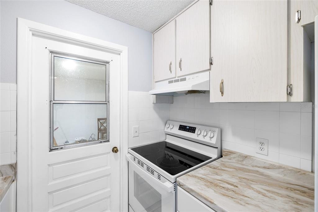 4930 Hazner Street New Port Richey, FL 34652 - Photo 10 of 22 a kitchen with white cabinets and a stove with wooden floor