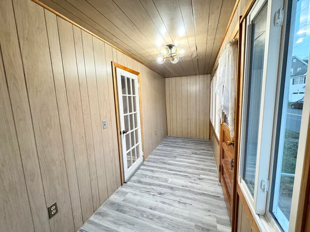 a view of a hallway with wooden floor and chandelier
