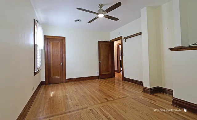 an empty room with wooden floor and a ceiling fan