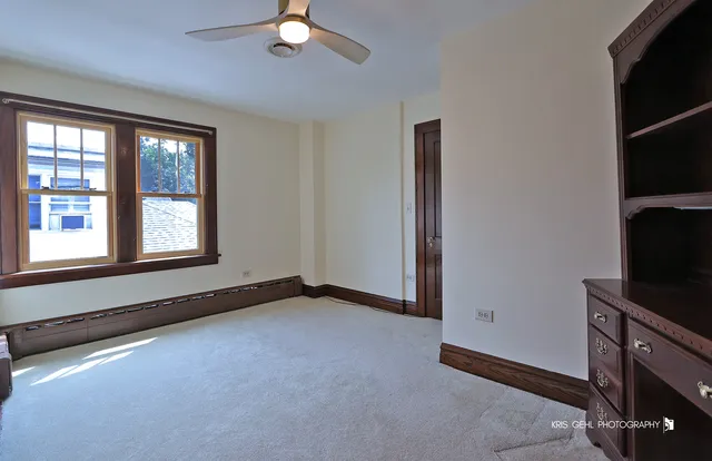 an empty room with windows and fan