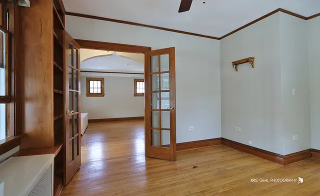 a view of empty room with wooden floor and fan