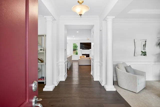 a view of a hallway with wooden floor and a livingroom with furniture