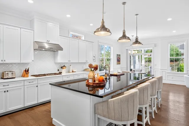a kitchen with stainless steel appliances granite countertop a sink a stove and chairs