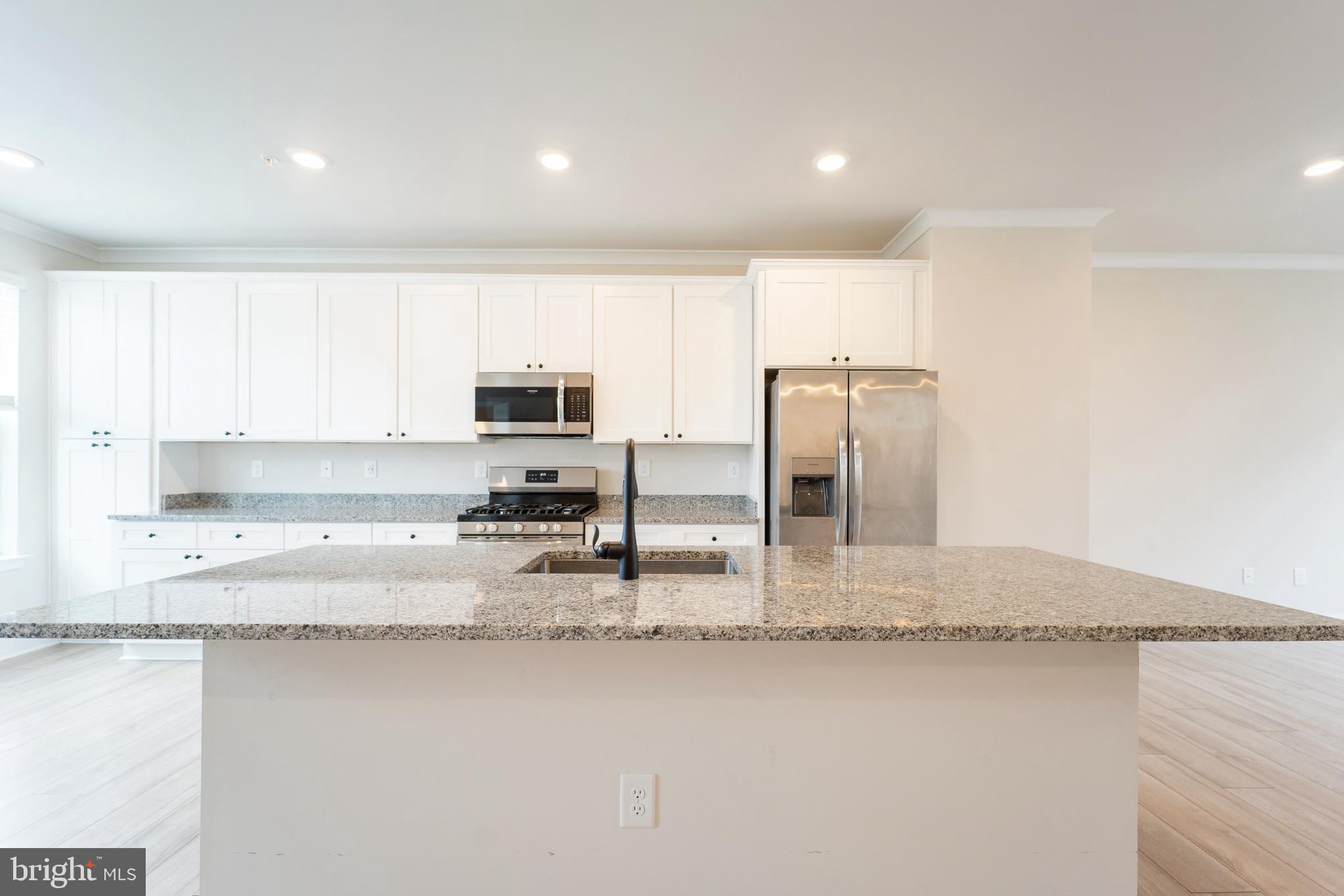 4334 Roland Heights Avenue Baltimore, MD 21211 - Photo 11 of 32 a kitchen with stainless steel appliances granite countertop a sink refrigerator stove and microwave
