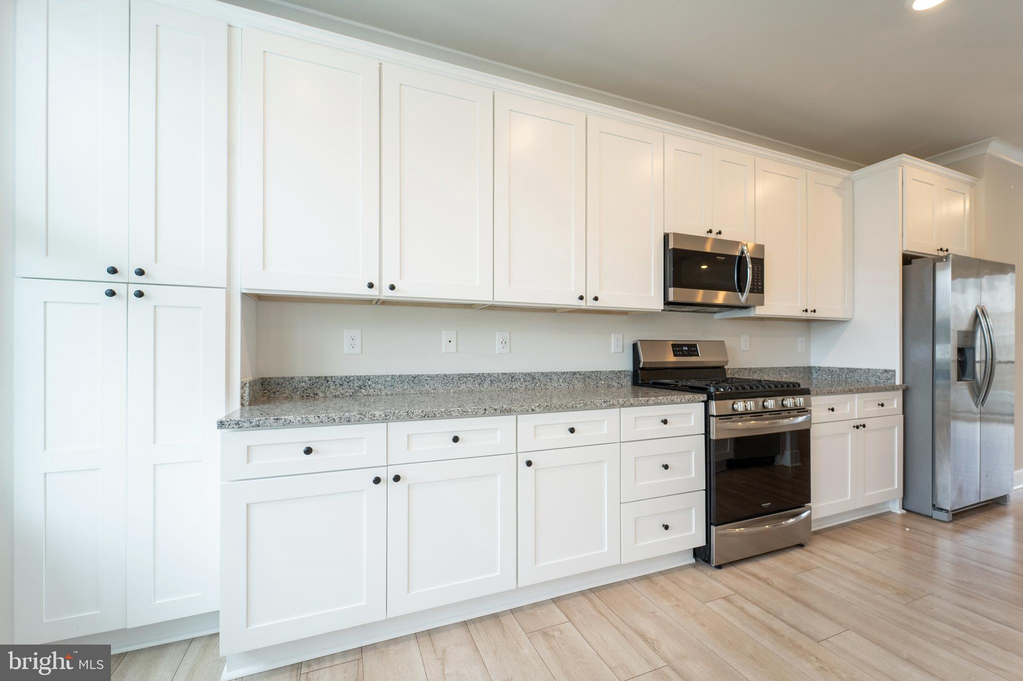 4334 Roland Heights Avenue Baltimore, MD 21211 - Photo 12 of 32 a kitchen with stainless steel appliances granite countertop a stove a sink and white cabinets