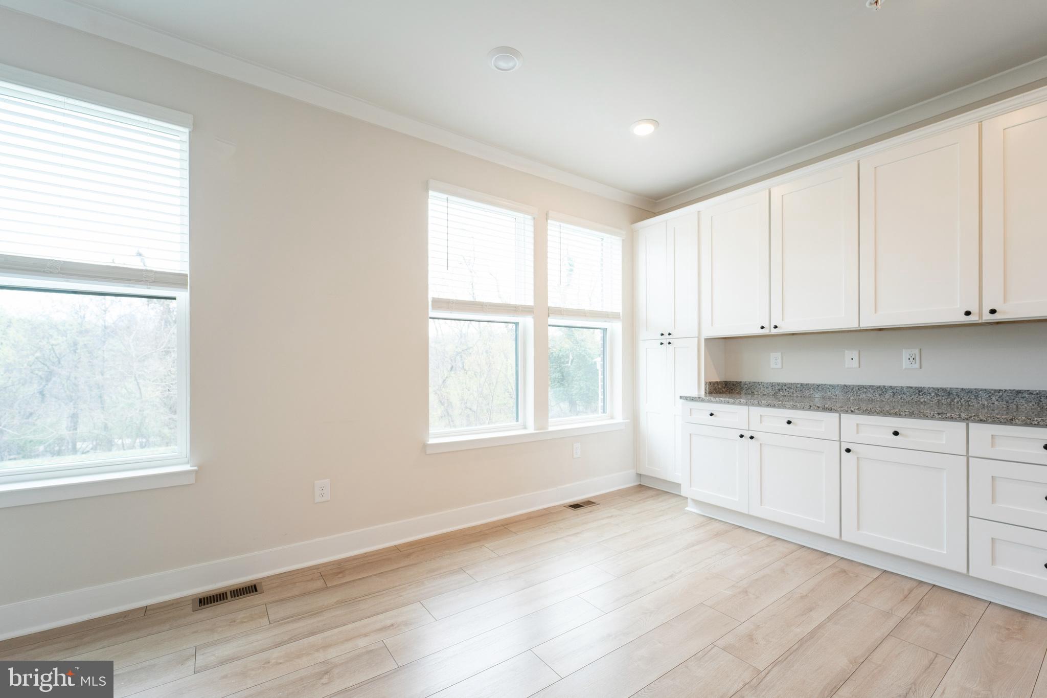 4334 Roland Heights Avenue Baltimore, MD 21211 - Photo 13 of 32 a large white kitchen with granite countertop white cabinets and a window