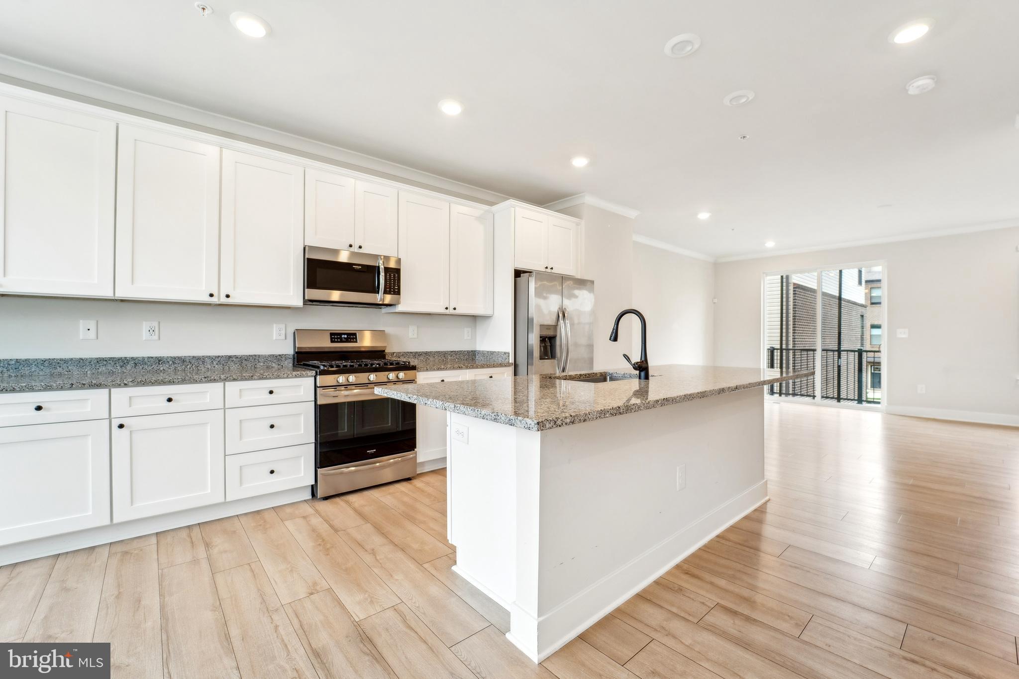 4334 Roland Heights Avenue Baltimore, MD 21211 - Photo 6 of 32 a kitchen with granite countertop white cabinets and stainless steel appliances