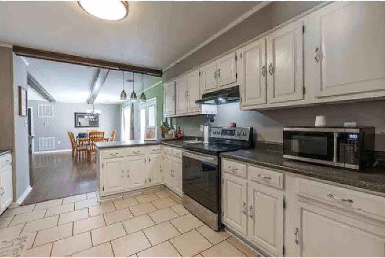 Kitchen featuring white cabinetry, dark countertops, tile flooring, and stainless steel appliances