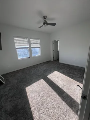 an empty room with windows and ceiling fan