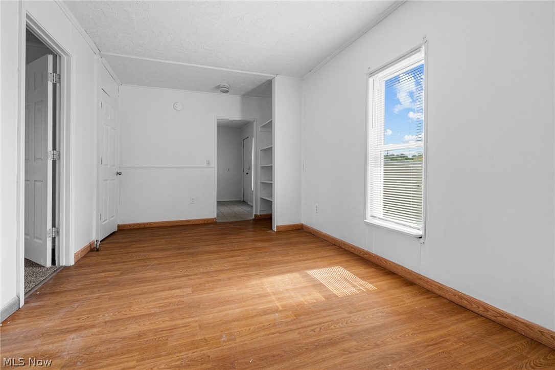 2387 29th Street Southwest Akron, OH 44314 - Photo 19 of 24 Empty room with a textured ceiling, light wood-style floors, and built in shelves