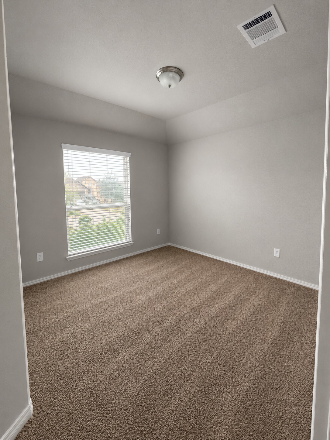 187 Limerick Road Buda, TX 78610 - Photo 15 of 18 A well-lit bedroom with fresh carpet and a view of the neighborhood through window blinds.