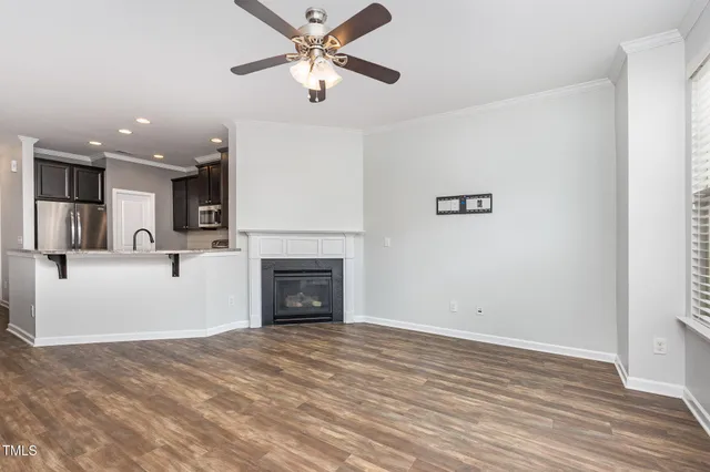 a view of a livingroom with a fireplace a ceiling fan and kitchen view