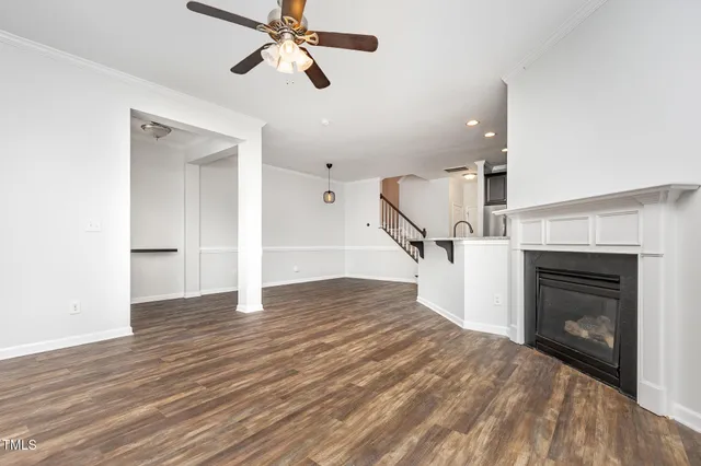 an empty room with wooden floor staircase and a fireplace