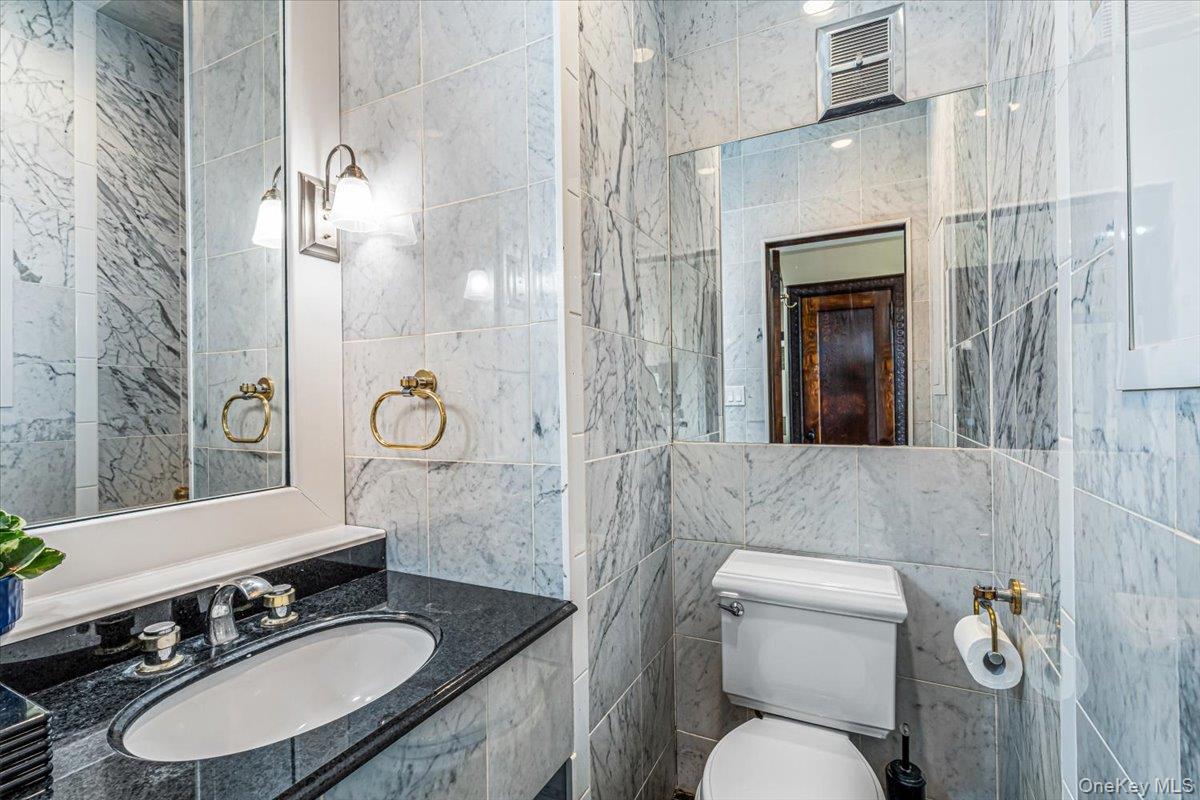 952 Cedar Swamp Road Glen Head, NY 11545 - Photo 43 of 50 a bathroom with a granite countertop toilet sink and mirror