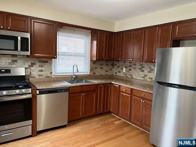 a kitchen with stainless steel appliances granite countertop a refrigerator stove a sink dishwasher and microwave