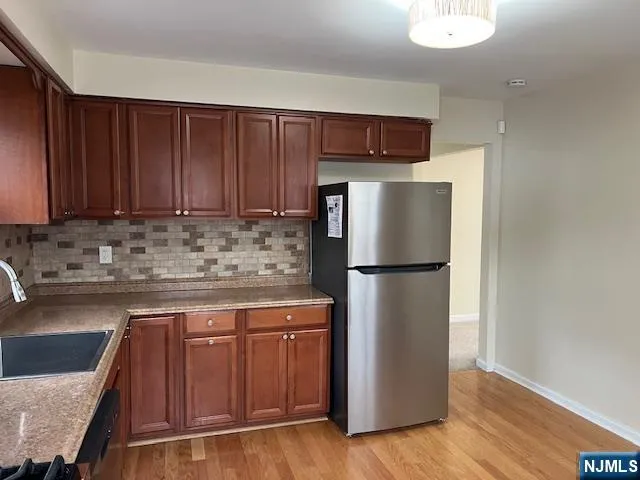 a kitchen with stainless steel appliances granite countertop a refrigerator a stove a sink and a microwave