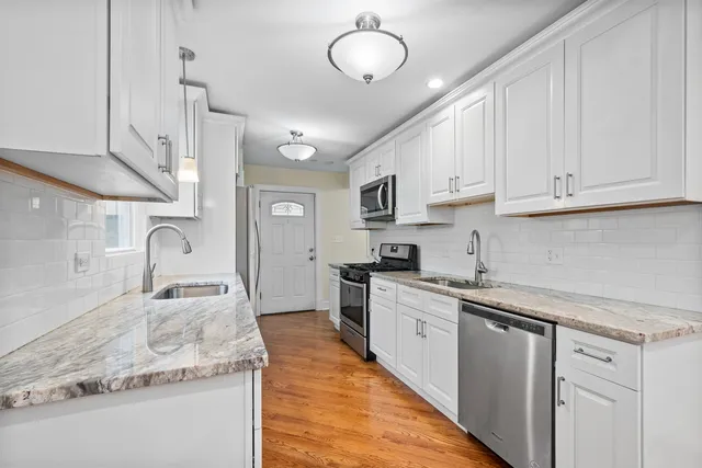 a kitchen with granite countertop a sink stainless steel appliances and cabinets