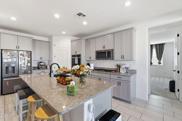a kitchen with stainless steel appliances granite countertop a stove top oven a sink a dining table and chairs