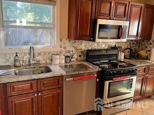 a kitchen with granite countertop a refrigerator stove and sink