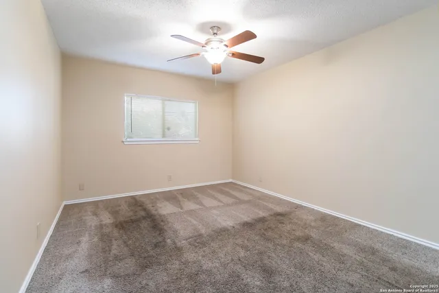 an empty room with a window and a ceiling fan